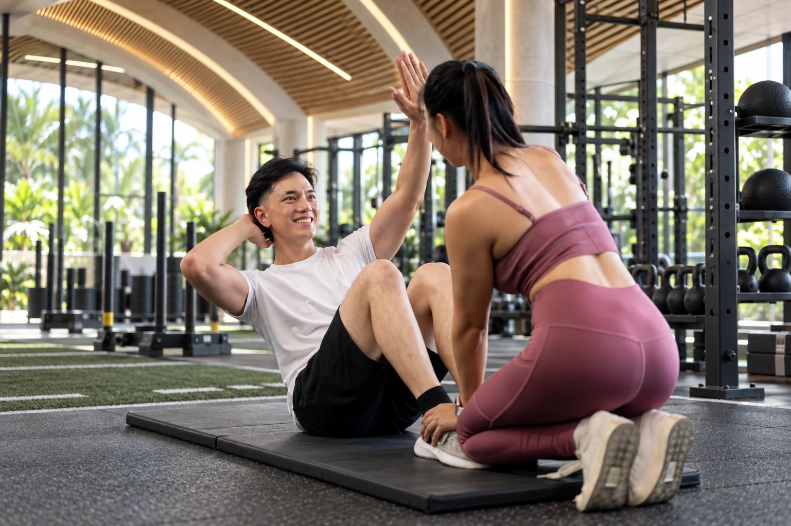 Supplied concept image of a man doing a sit-up and sharing a high five with his training partner